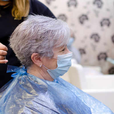 Mujer mayor en la peluquería con mascarilla para evitar el cont